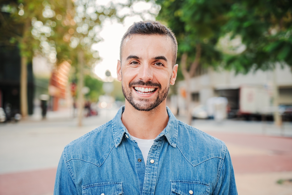 A man smiling confidently outdoors in a plaid shirt with arms crossed - Seattle Dentist