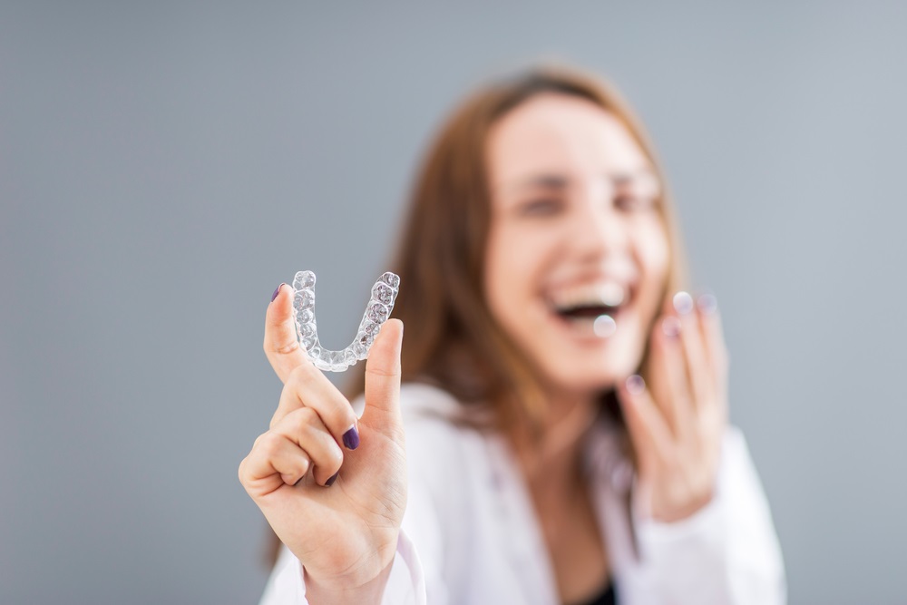 woman is holding an invisalign brace - Invisalign in Seattle