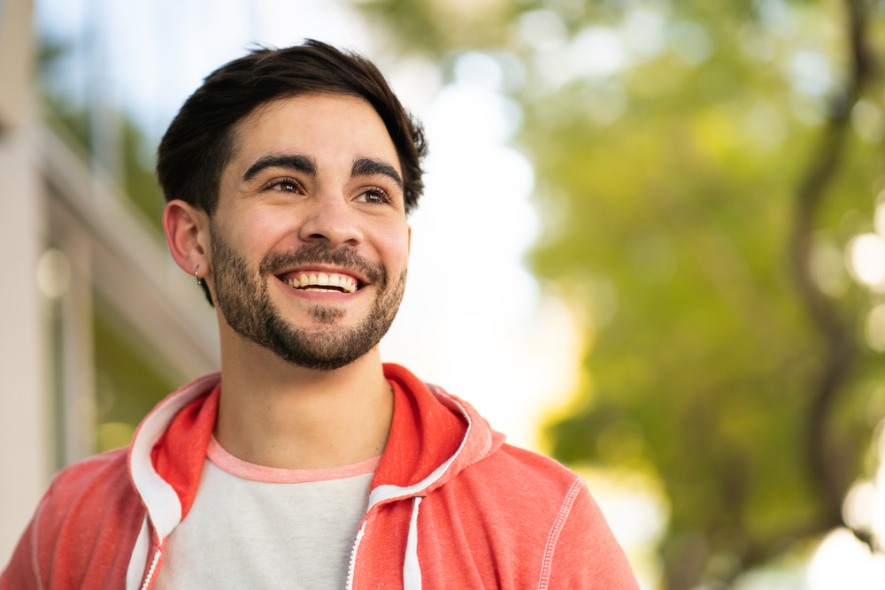 A man smiling confidently outdoors in a plaid shirt with arms crossed - Seattle Dentist